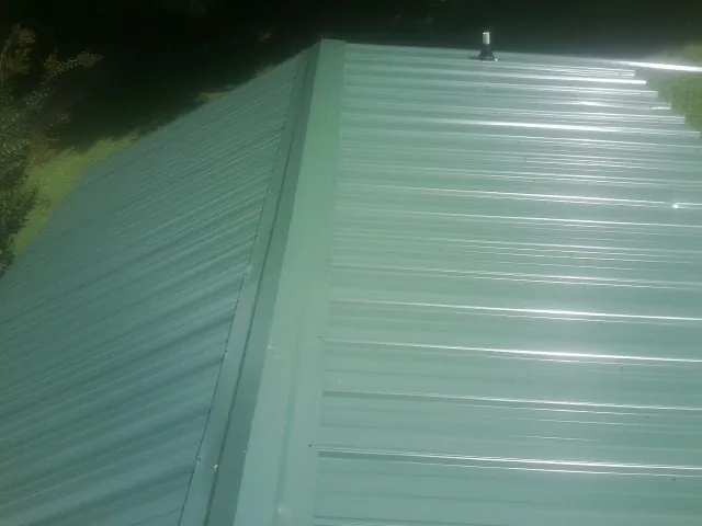 New green metal panels meeting at the ridge of a roof — Flat Roof Repair work by our crew in Hunlock Creek