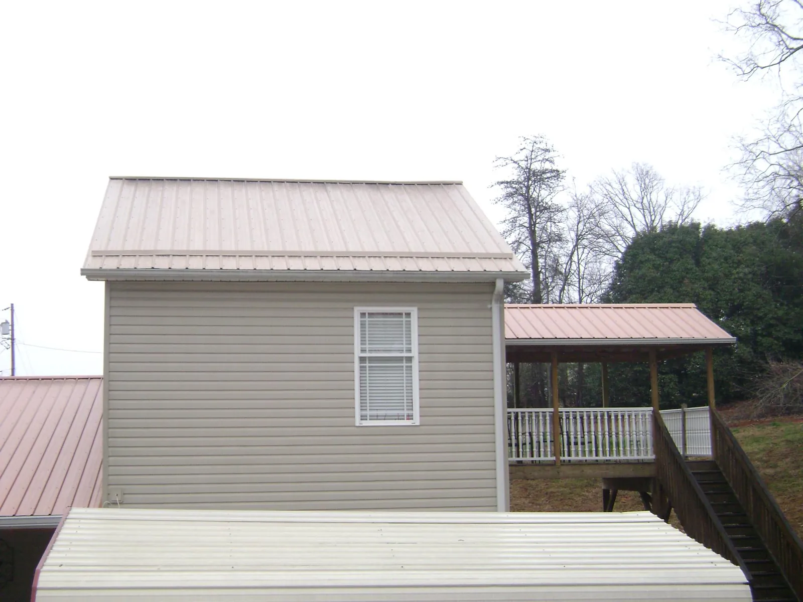 Tan metal roofs on a two story addition and attached porch, from a Roof Replacement job in Hunlock Creek