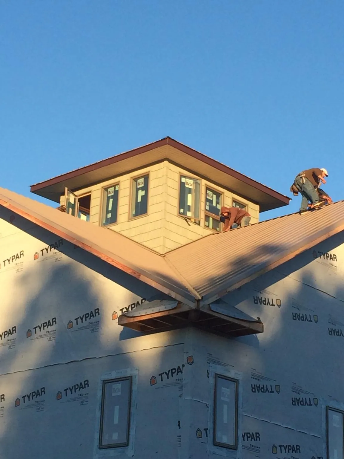 Roofers working around a rooftop cupola on a new metal roof at sunset — Roof Waterproofing in Hunlock Creek by Roofing Brothers